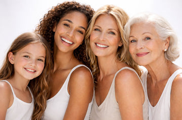 Four women of different ages smiling together against a white background