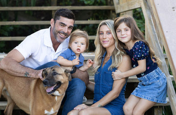 Family of four with a dog sitting outdoors on wooden steps.